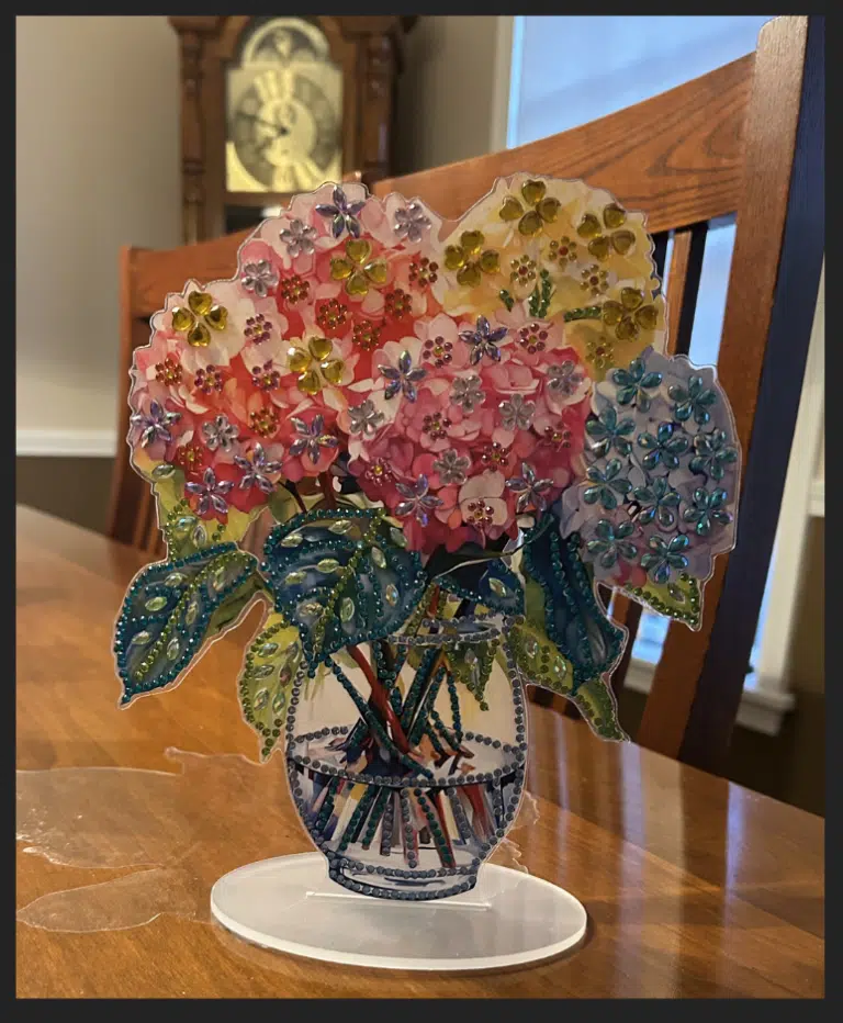 Colorful three-dimensional craft featuring blue, yellow, and pink hydrangeas in vase embellished with sparkley Diamond Art stickers.