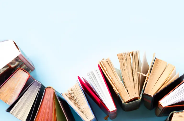 Row of books propped up on end like dominos, seen from above.