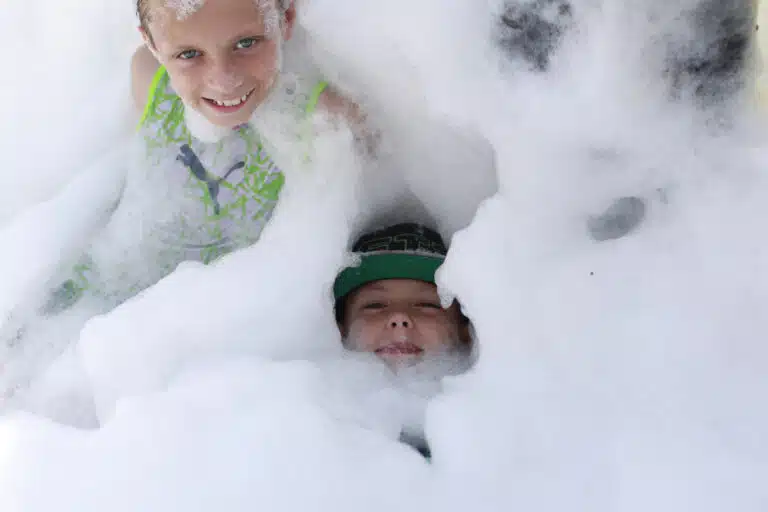 Two children playing in big pile of foam.