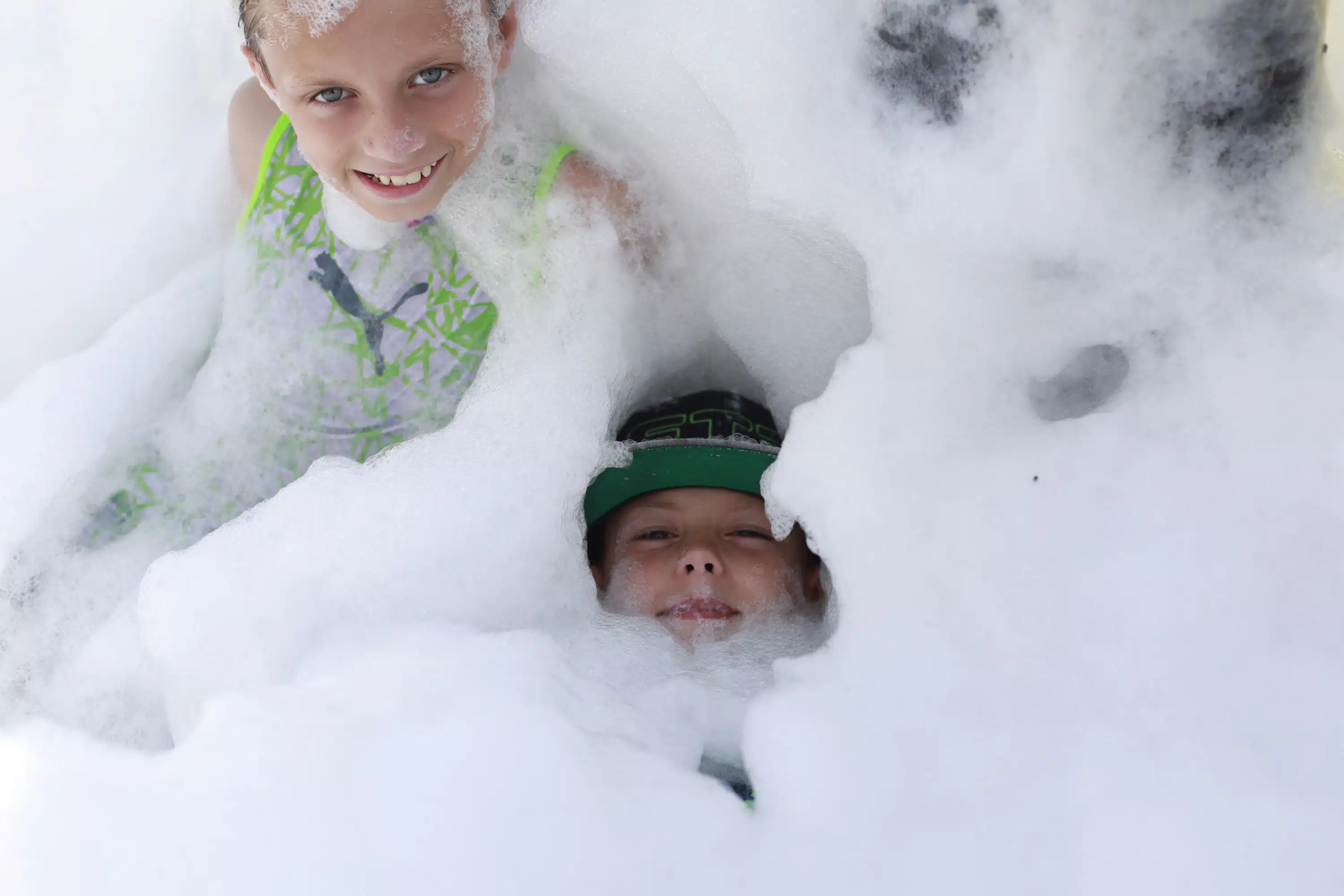 Two children playing in big pile of foam.