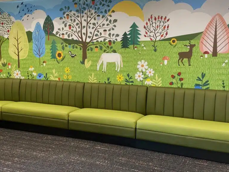 Huntingburg Public Library's children's area, with comfortable seating and a bright wall mural featuring woodland animals.