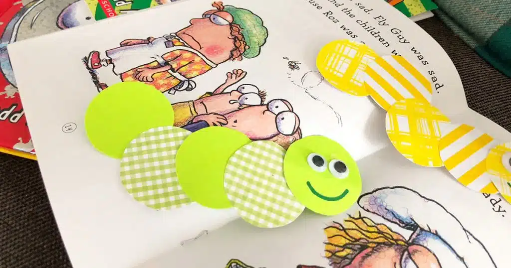 Open children's picture book, with bookworm bookmarks made of colorful green and yellow paper circles.