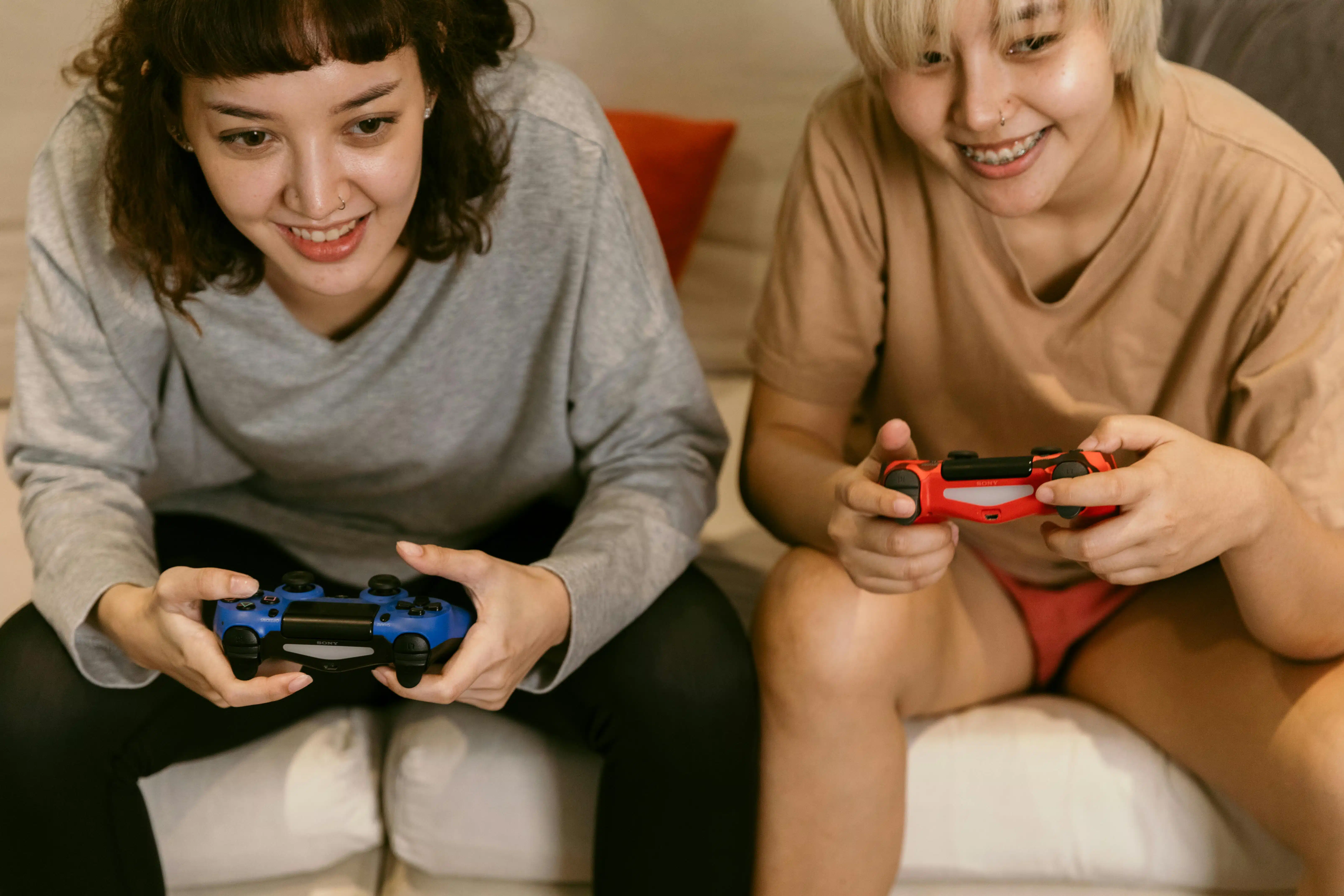 Two teen girls smiling and laughing while they play a video game together.