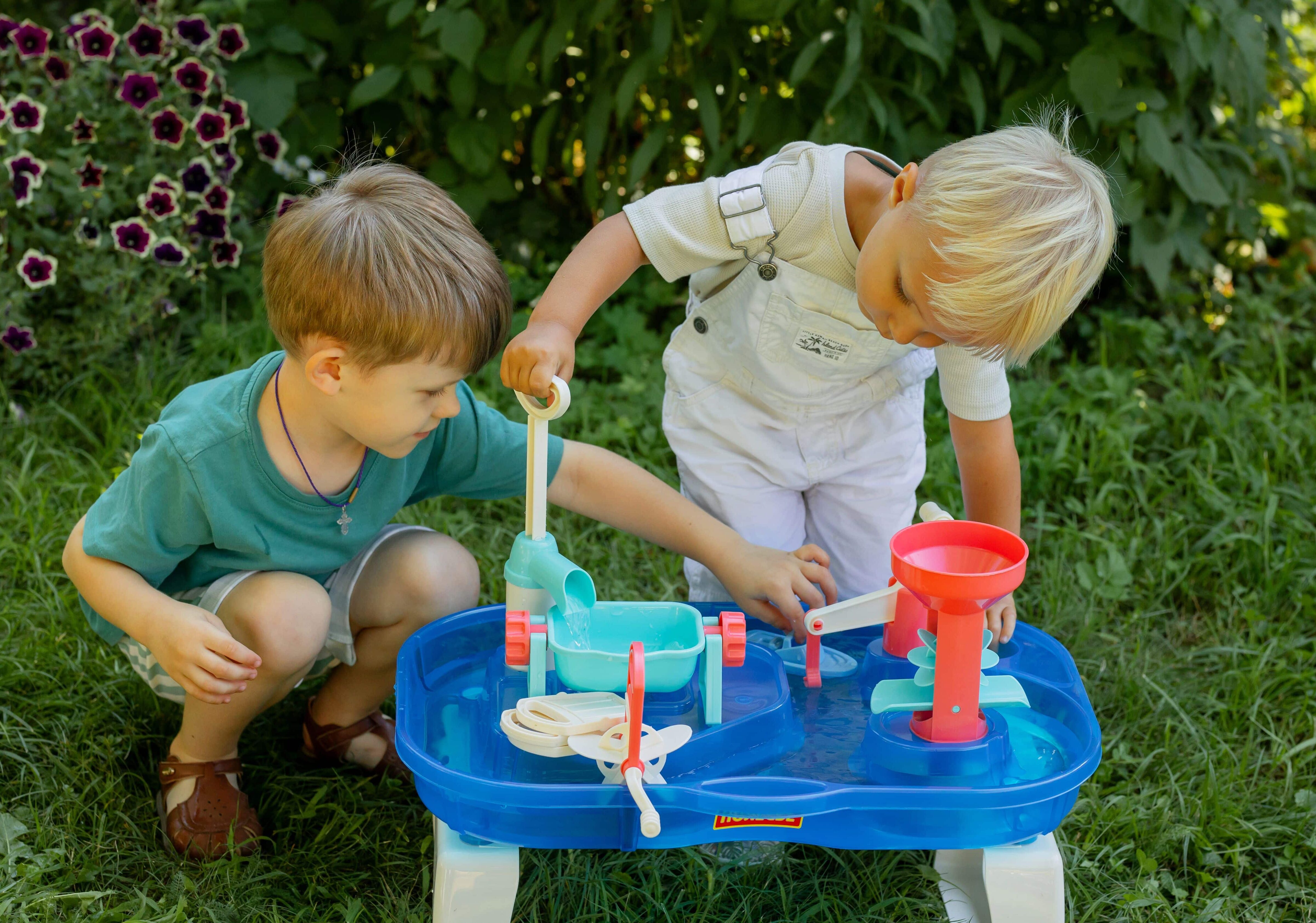 Two young boys playing with a water table toy.