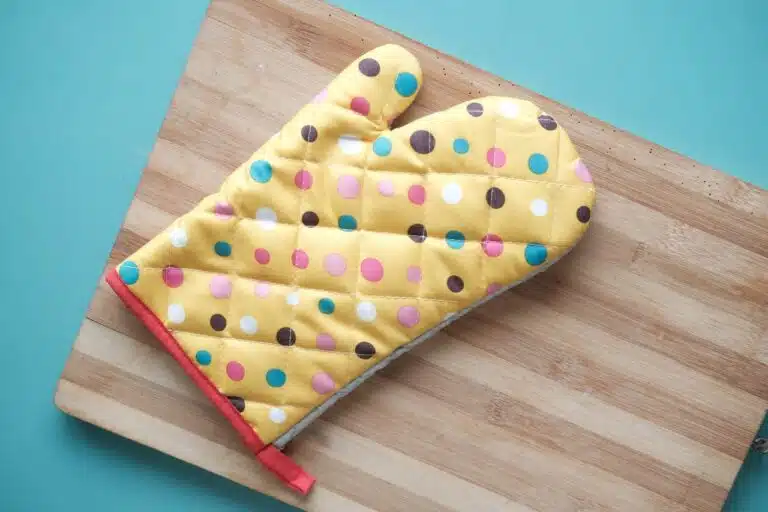 Polka dot oven mitt on a wood cuttingboard.