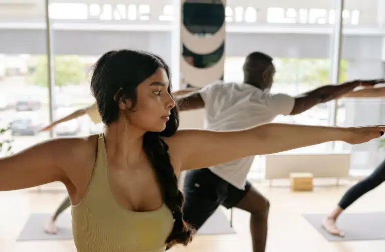 Man and woman doing yoga stretches at class.